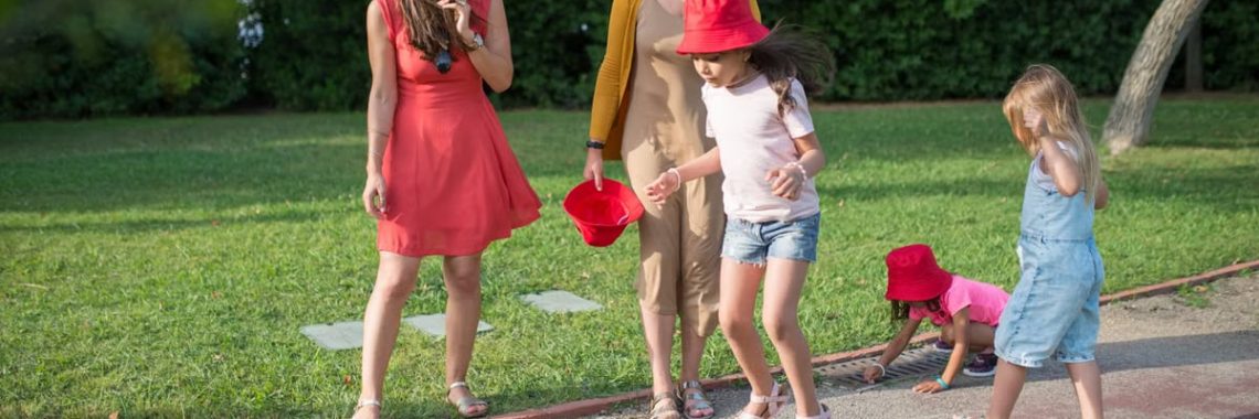 A joyous family experience in a lush Portugal park, featuring playful activities between young girls and adults.
