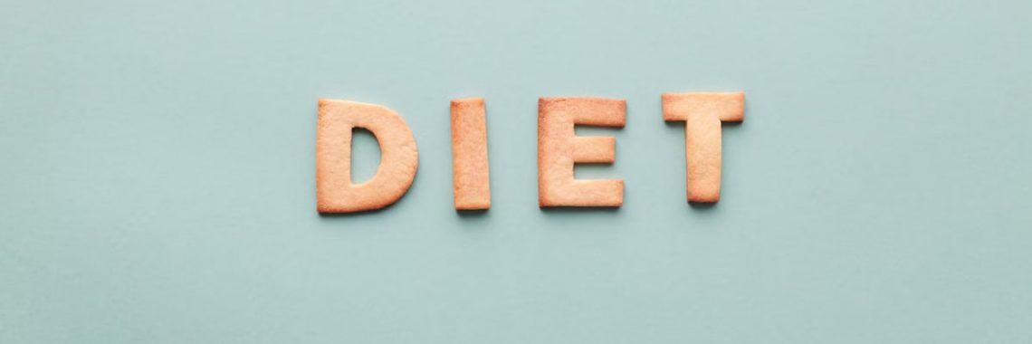 Alphabet cookies spelling 'diet' on a soft turquoise background, shot as a flat lay.